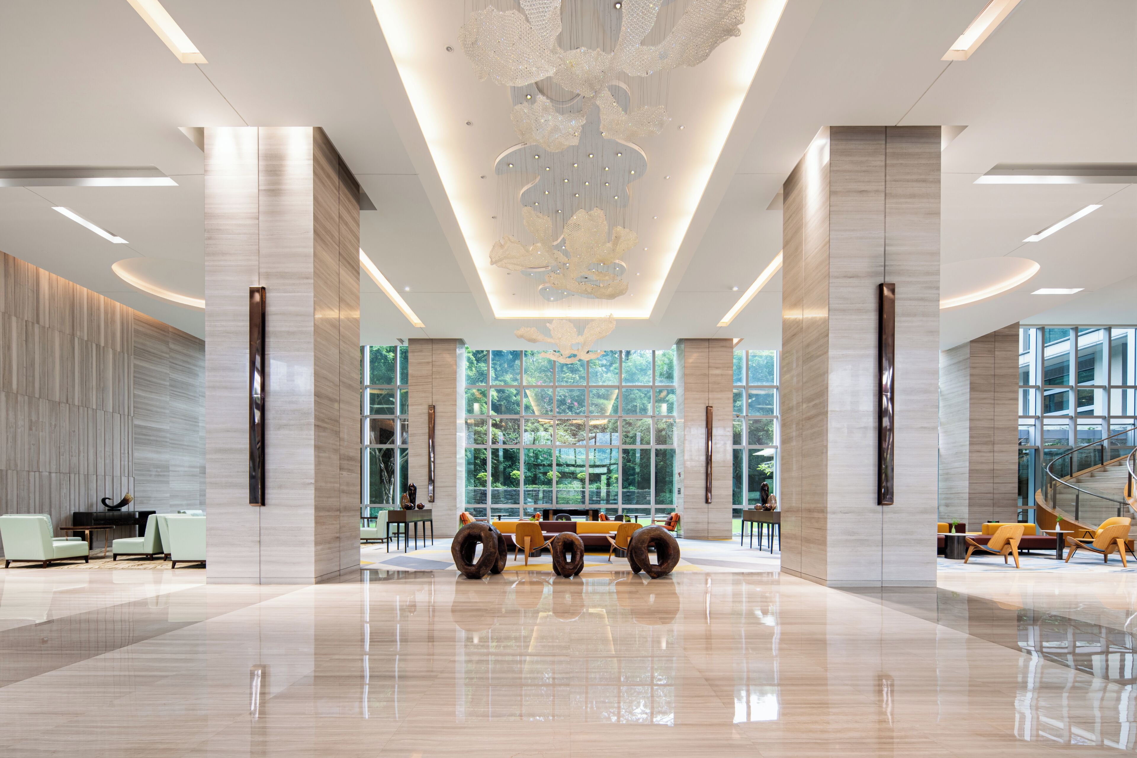 A spacious lobby with a modern chandelier, large windows, and a piano.
