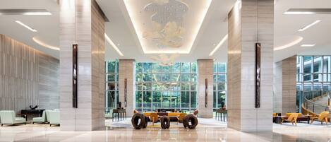 A spacious lobby with a modern chandelier, large windows, and a piano.