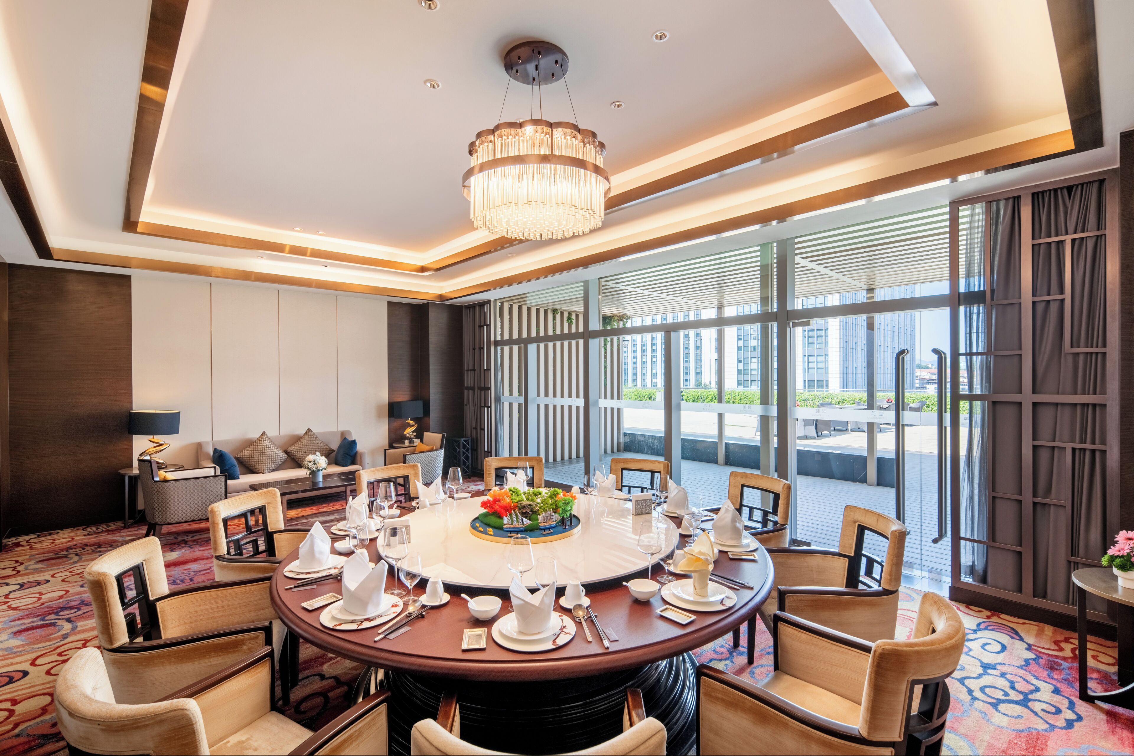 A hotel dining room with a round table set for a meal, surrounded by chairs.