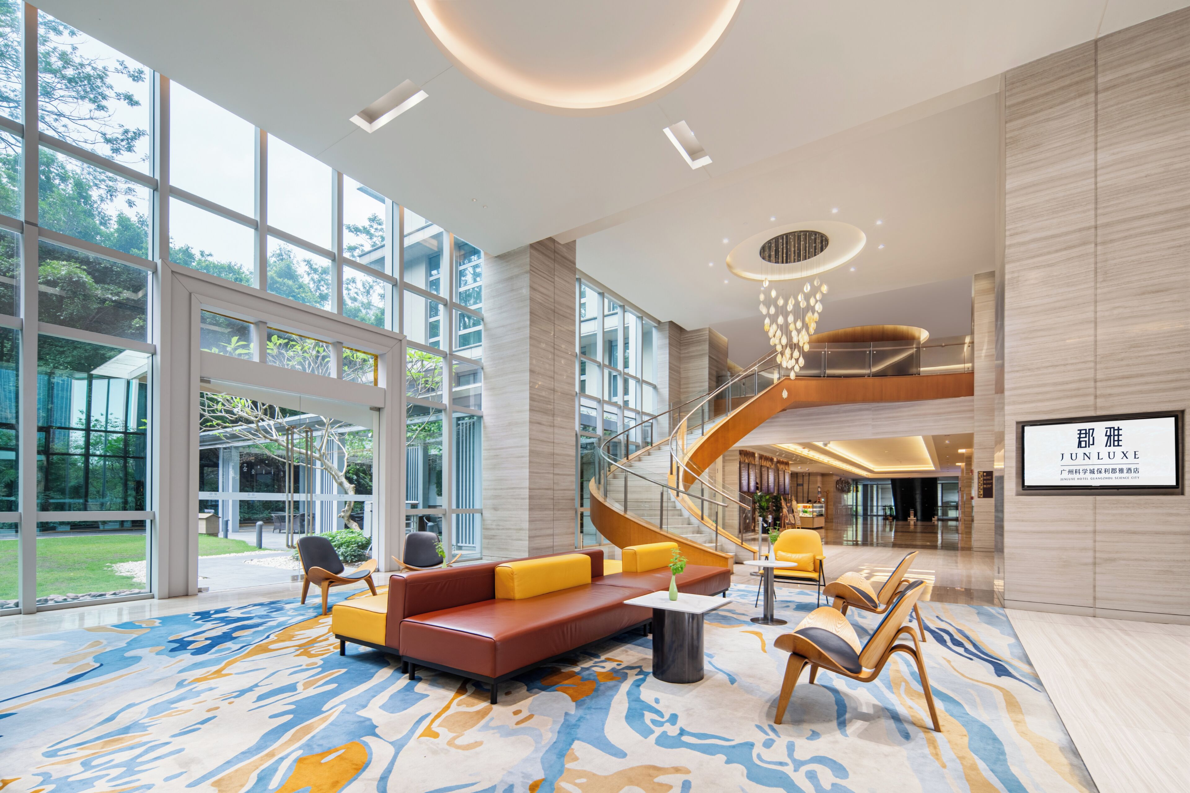 A spacious lobby with a modern staircase, comfortable seating, and large windows offering views of the outdoors.