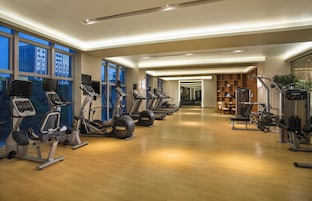 Un gimnasio moderno con máquinas de cardio, estaciones de pesas y suelo de madera.