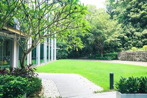 A modern building with a well-maintained lawn, a paved pathway, and lush greenery.
