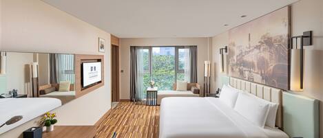 A hotel room with two beds, a desk, a chair, a window with a view, and a painting on the wall.