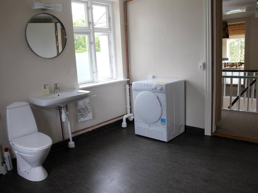A small, clean bathroom with a toilet, sink, and washing machine.