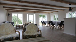 Una habitación espaciosa con vigas de madera, un comedor con mesa y sillas, y un sofá con un cubrefrío mullido.