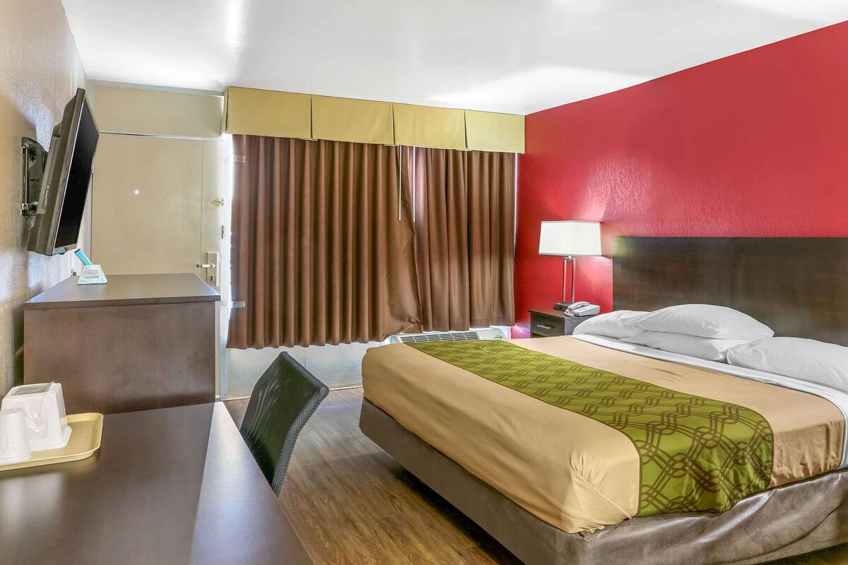 Una habitación de hotel con cama, mesita de noche y escritorio con silla.