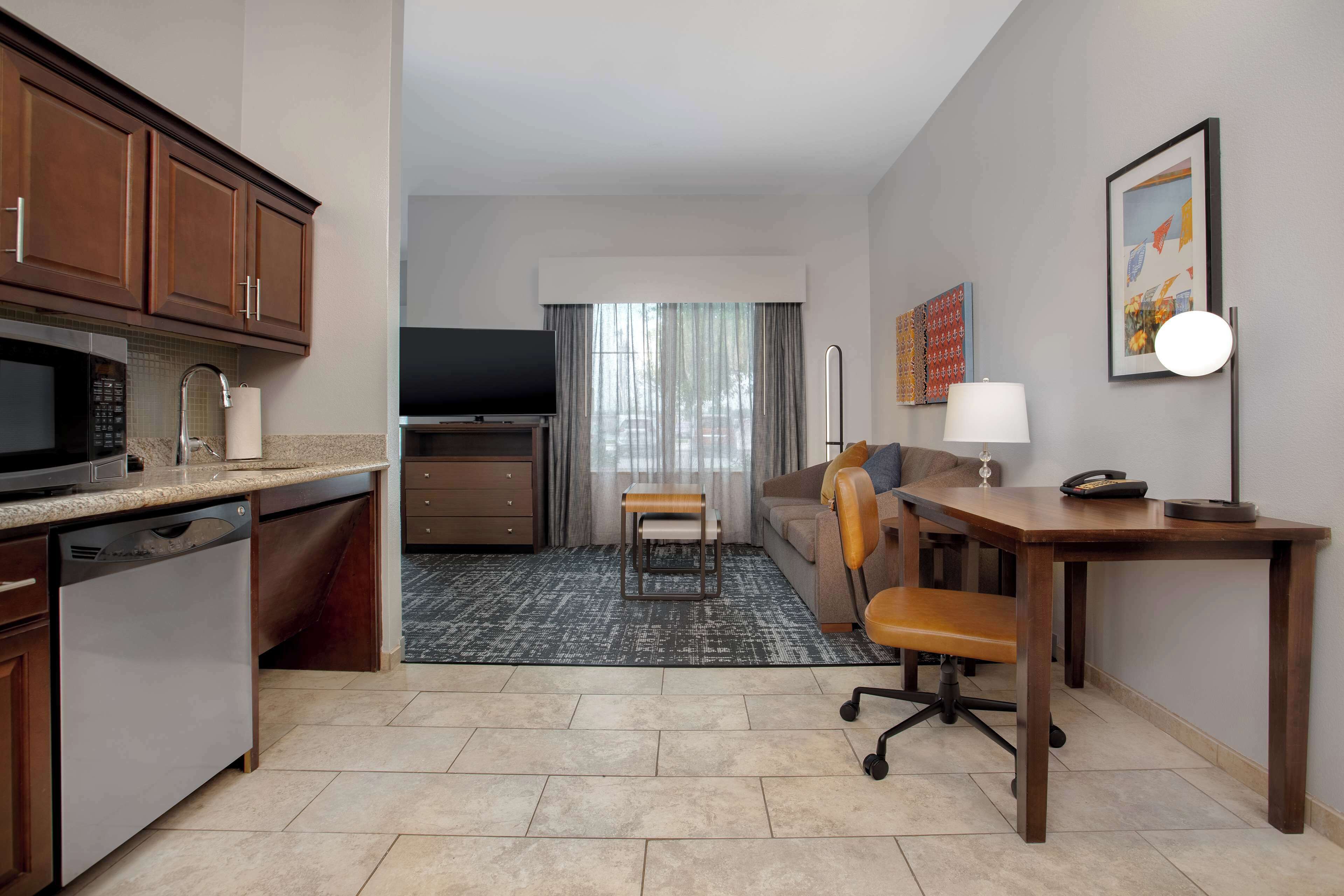 A compact hotel room with a kitchenette, a dining area, and a seating space.