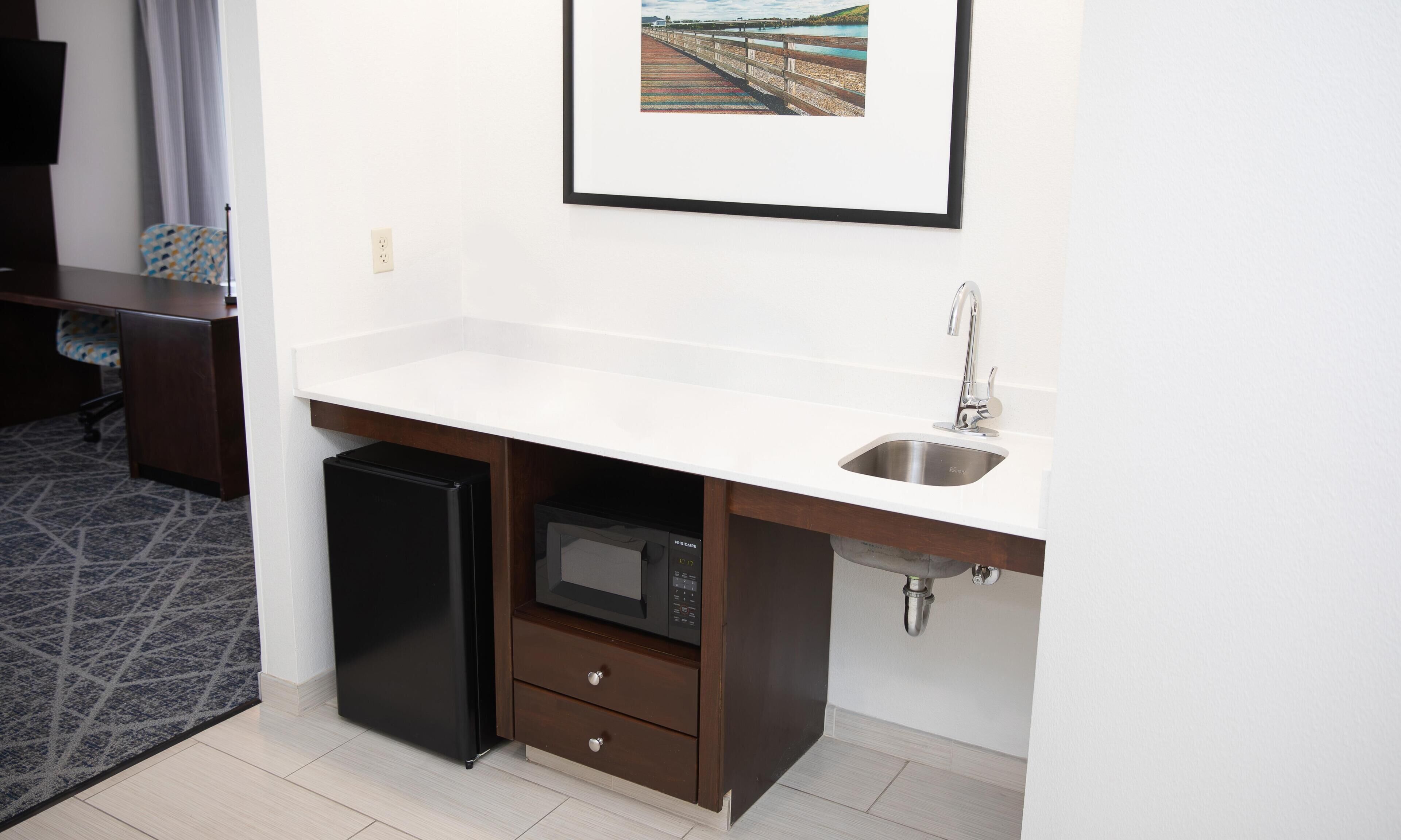 A compact kitchenette with a built-in microwave, a sink, and a small refrigerator.