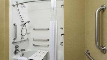 A bathroom with a bathtub, a shower with grab bars, and a toilet with a safety bar.