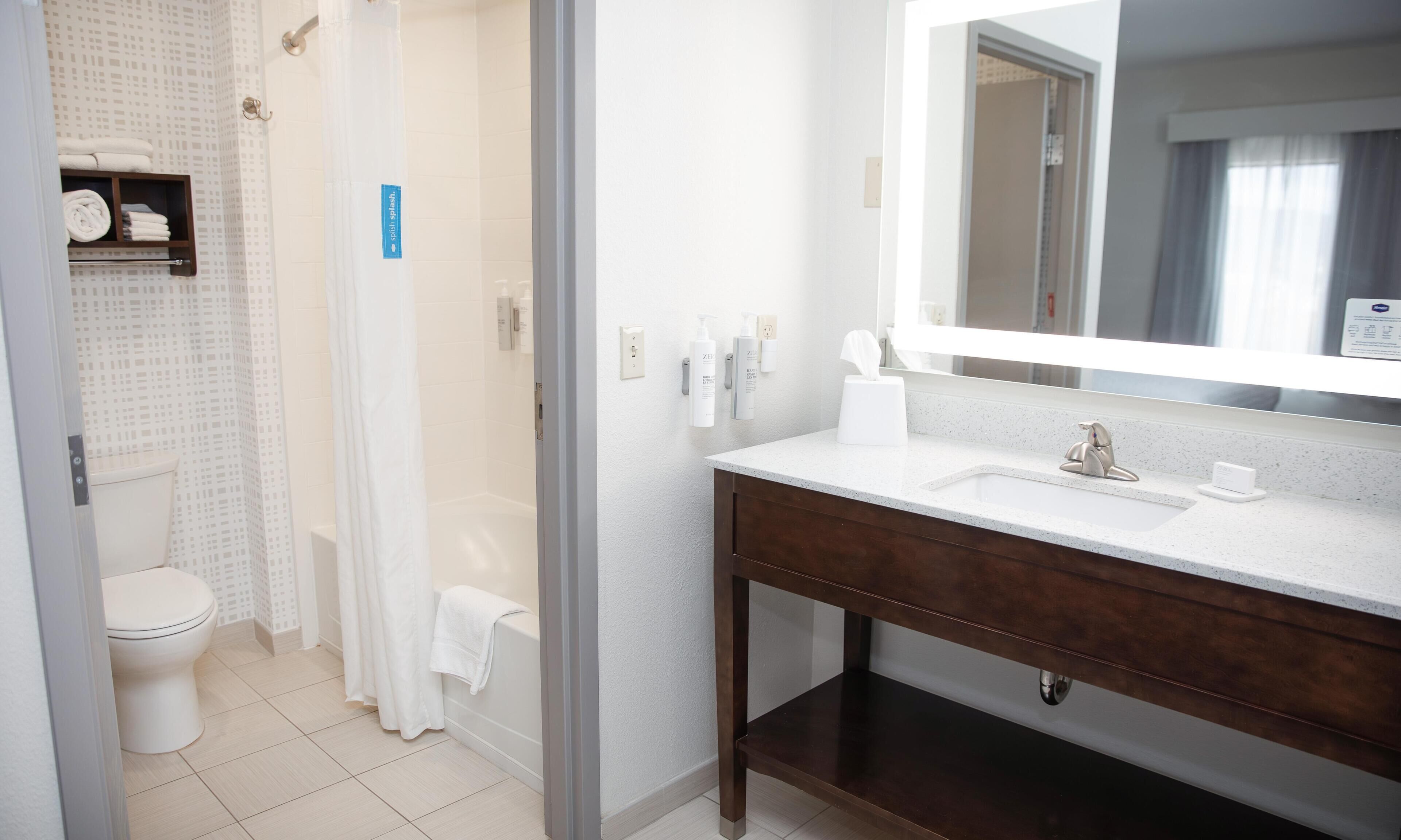 A modern bathroom with a toilet, shower, and sink.