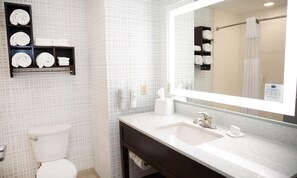 Une salle de bain avec des toilettes, un lavabo avec un miroir et des étagères avec des serviettes.