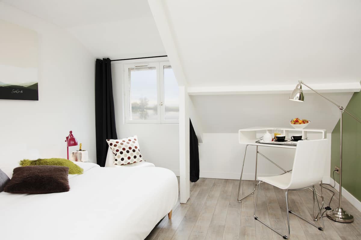 Une chambre moderne avec un lit, un bureau et une chaise. Il y a une fenêtre avec des rideaux, une lampe et un tableau au mur.