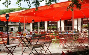An outdoor café with red umbrellas, tables, and chairs. - Les Canisses (Saint-Pierre-la-Garenne)