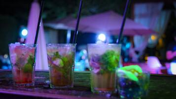 Un bar où l’on voit plusieurs verres de cocktails, chacun agrémenté d’une paille et décoré de quelques feuilles de menthe.
