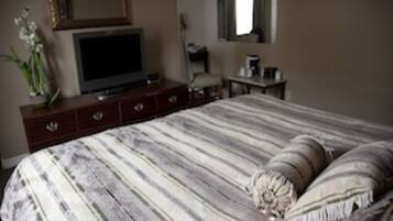 Un dormitorio con cama, cómoda, televisor y espejo.