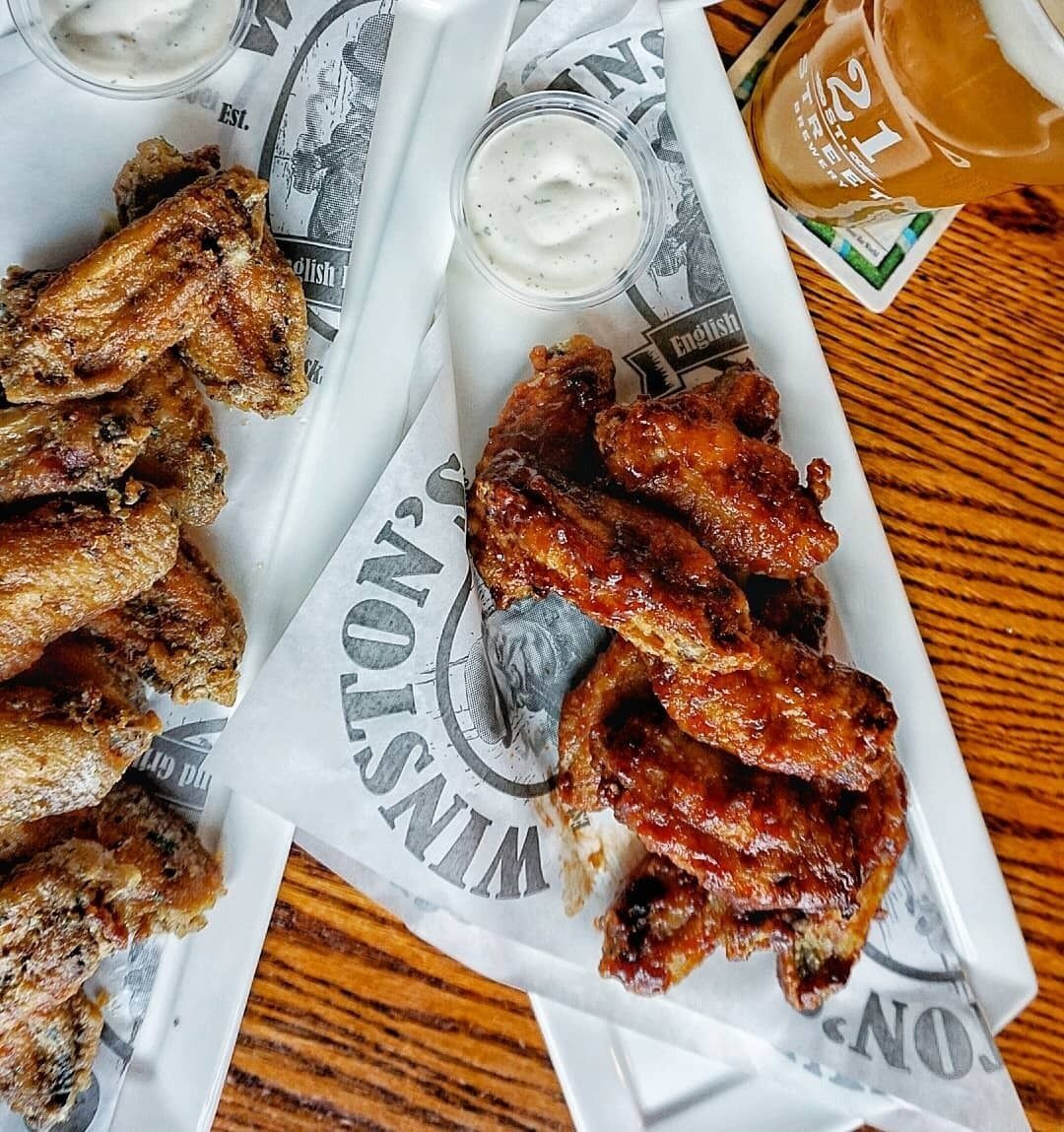 A tray with wings and dipping sauces on a wooden table.