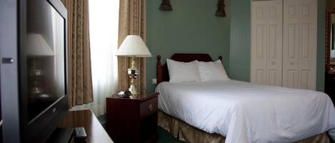Ein Hotelzimmer mit Bett, Fernseher, Lampe und Kleiderschrank.