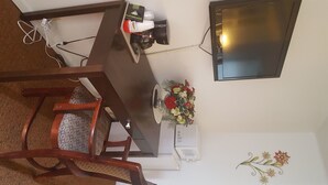 A dining area with a wooden table, chairs, a vase of flowers, and a mounted flat-screen TV. - Sonoma Lodge (Bend)