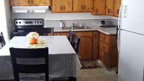 A compact kitchen with wooden cabinets, a stove, a sink, and a refrigerator. - Sonoma Lodge (Bend)