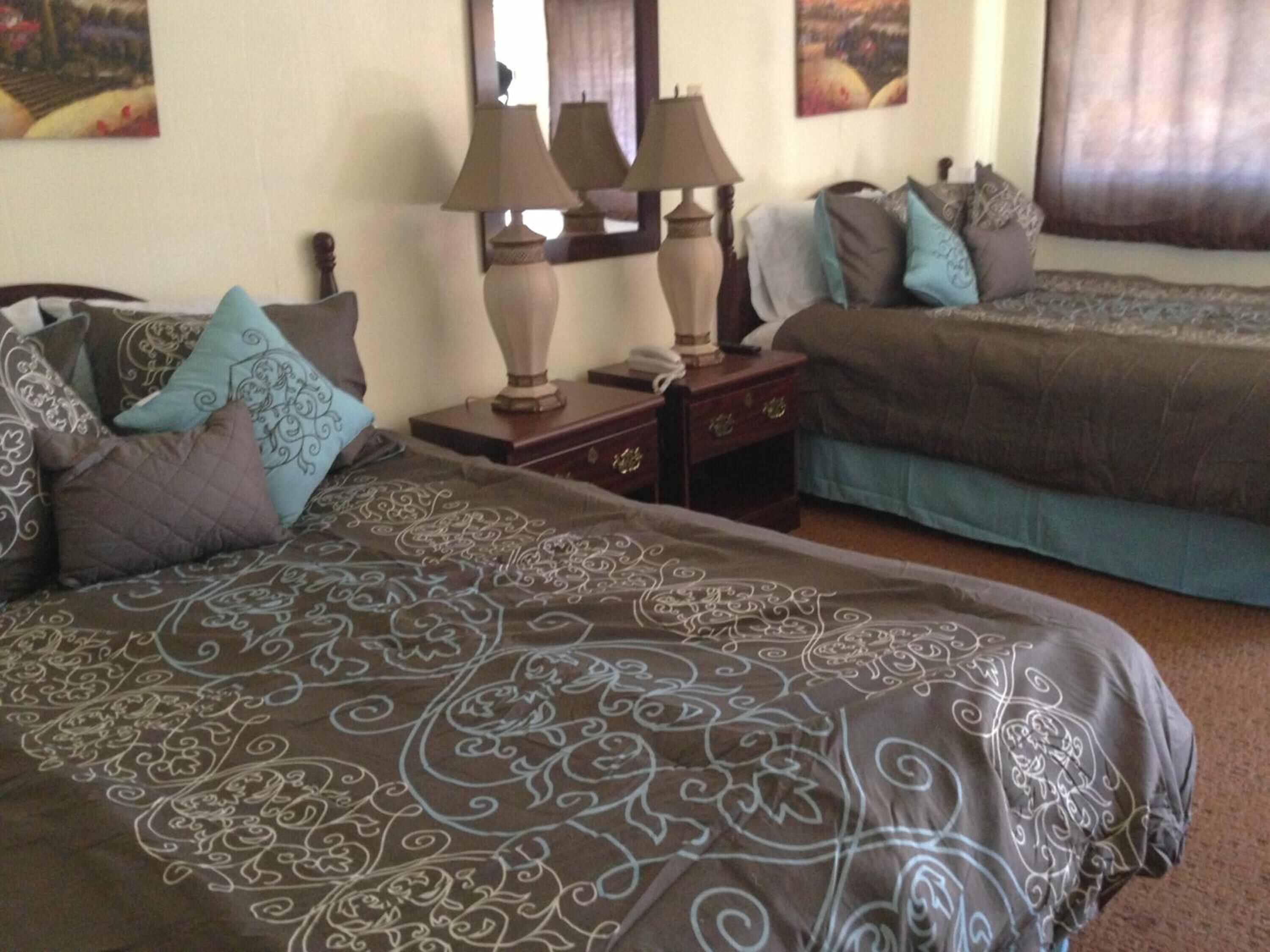 A hotel room with two beds, a nightstand with lamps, and decorative pillows.
