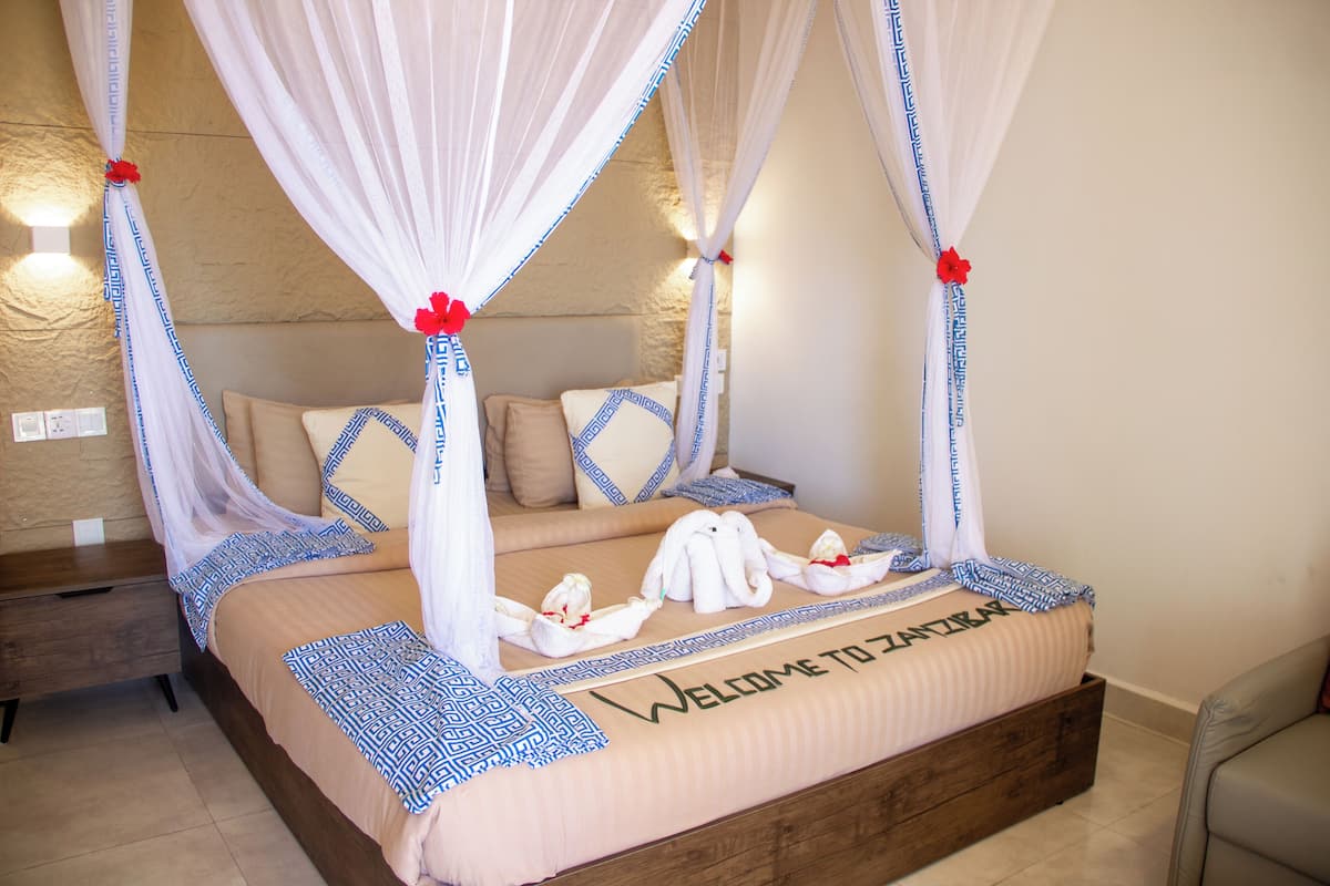 A four-poster bed with a canopy, a wooden headboard, and a welcome mat.