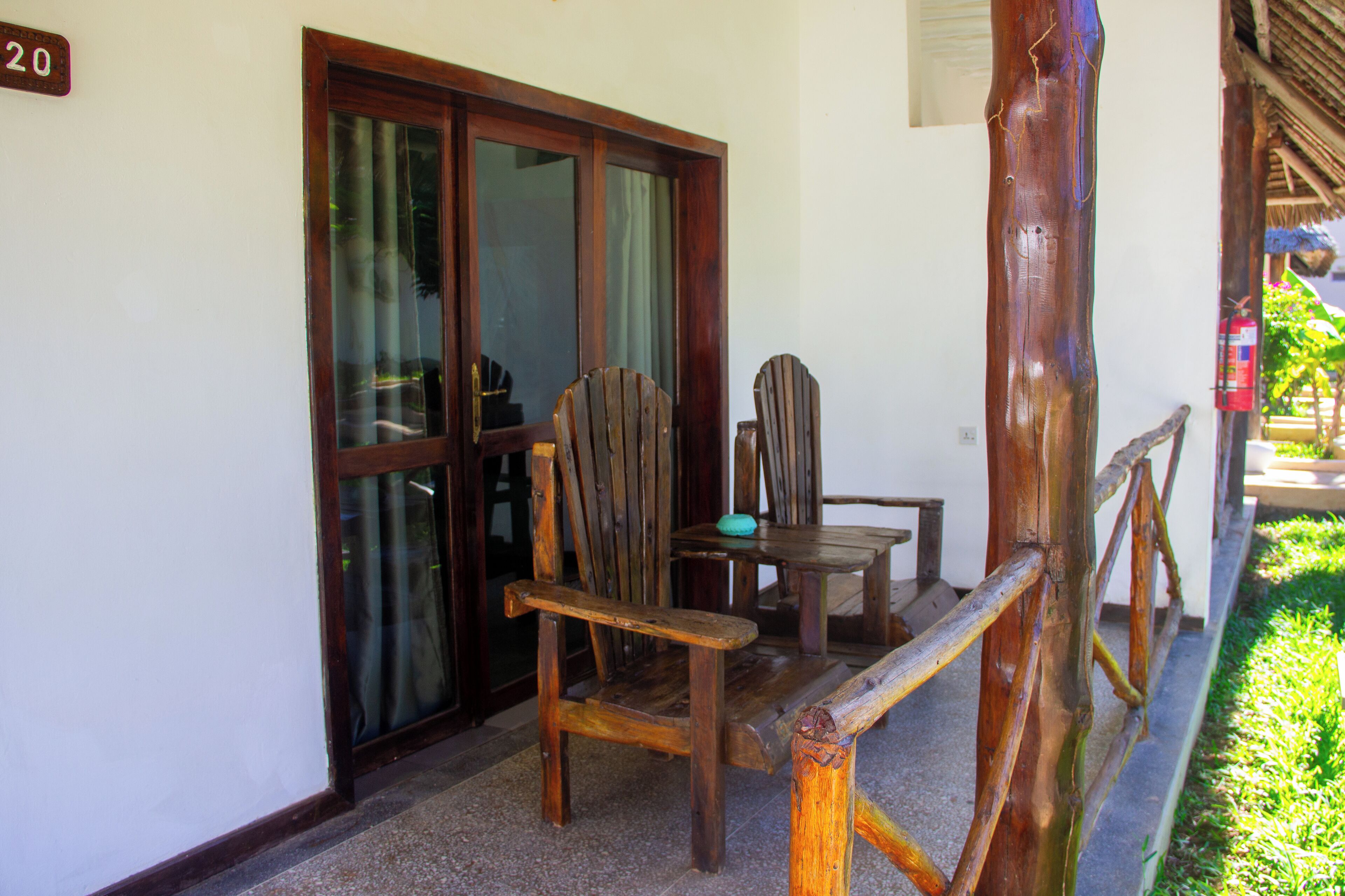 A wooden chair and table set against a white wall, with a wooden railing and a door with glass panels.
