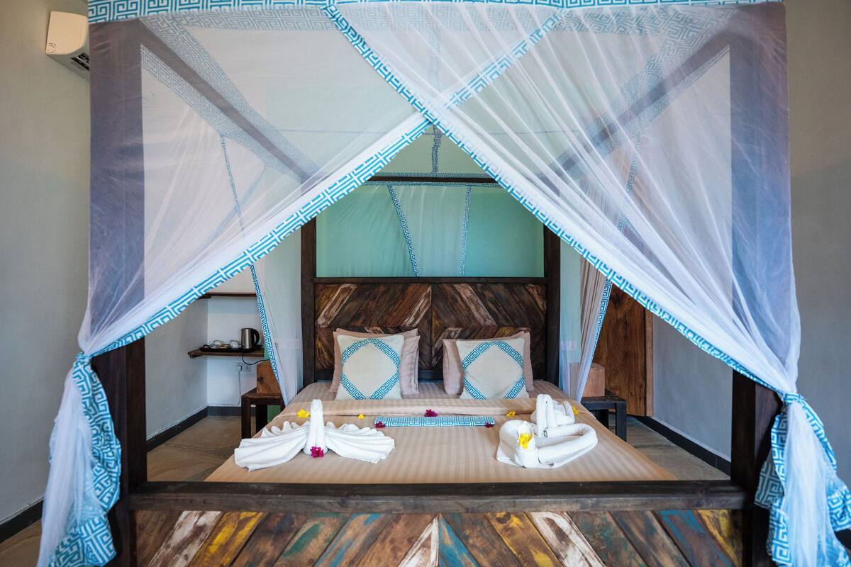 A bed with a canopy, wooden headboard, and a patterned floor.