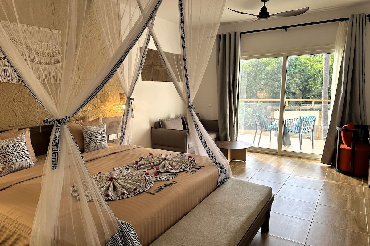A spacious bedroom with a large bed, a canopy, and a view of the outdoor area.