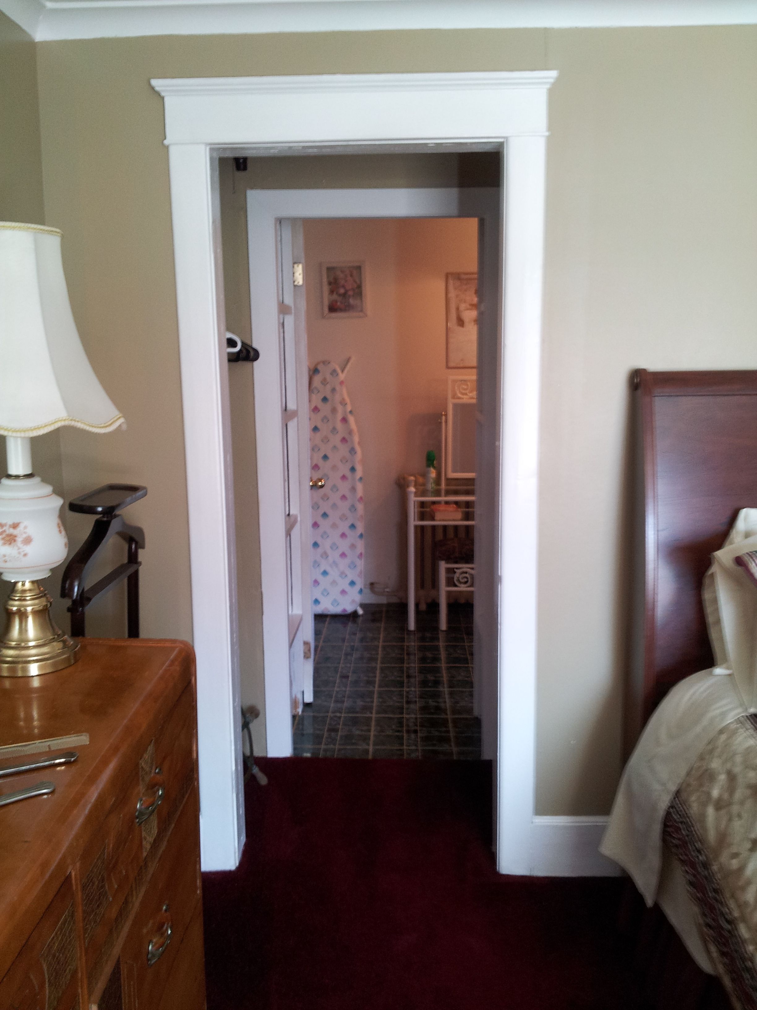 A narrow hallway leading to a bathroom with a shower, a small table, and a mirror. A wooden dresser with drawers is visible on the left.