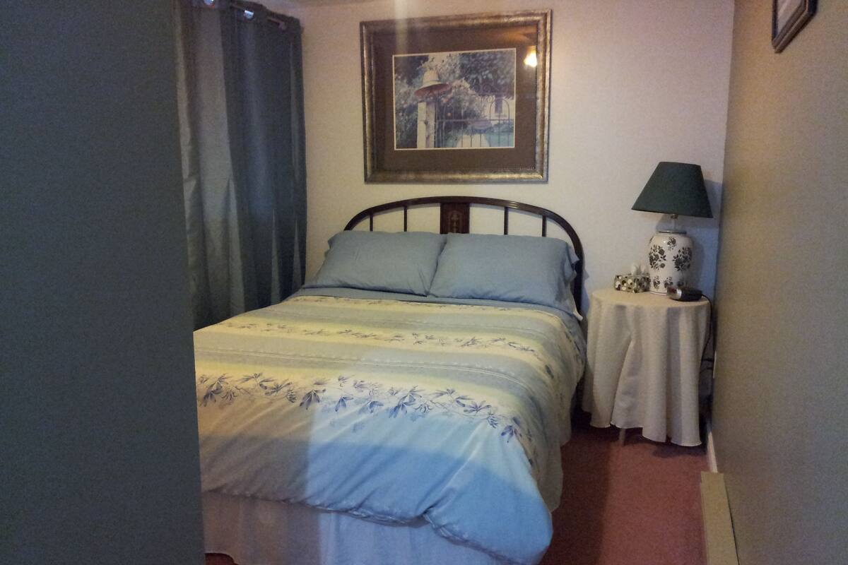 Une chambre à coucher avec un lit, une table de chevet, une lampe et un tableau encadré au mur.