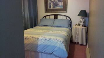 Un dormitorio con una cama, una mesita de noche, una lámpara y un cuadro en la pared.