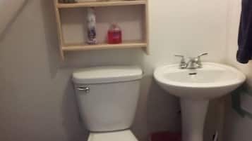 Een compacte badkamer met toilet, wastafel en planken boven het toilet.