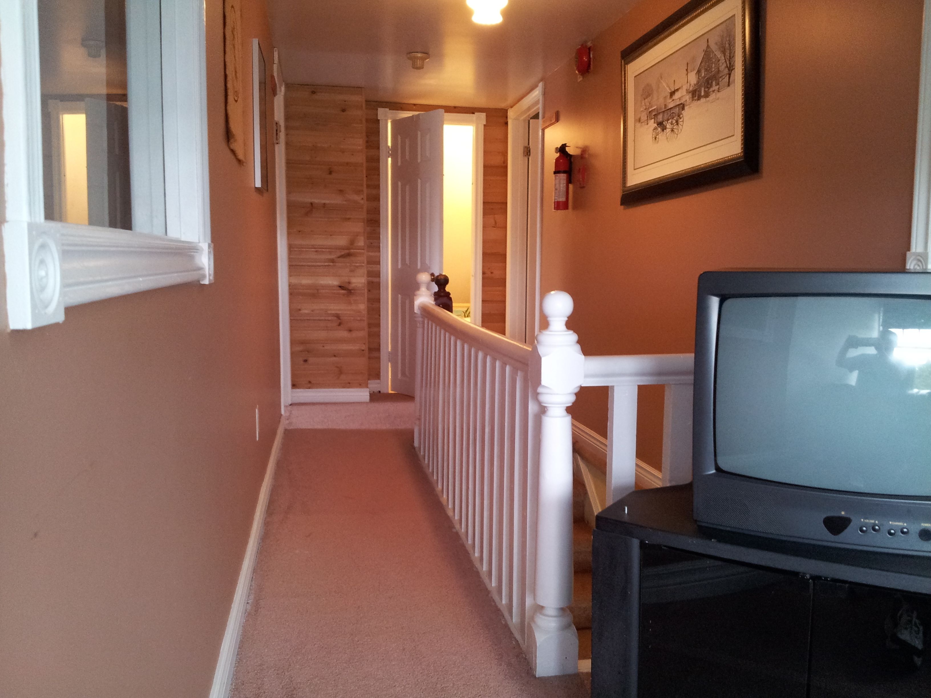 A hallway with wooden walls and a white railing.