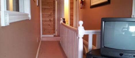 A hallway with wooden walls and a white railing.