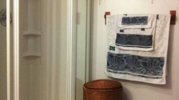 Ein Badezimmer mit einer Glasdusche, einem Korbwäschesammler und einem Wäschekorb.