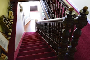 Eine Treppe mit rotem Teppich und einer Holzwandung mit Verzierungen.