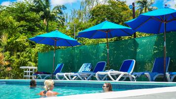 Una piscina al aire libre, sombrillas, sillones reclinables de piscina