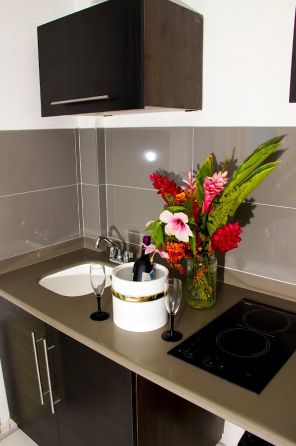 A kitchen with a built-in oven, a sink, and a vase with flowers.
