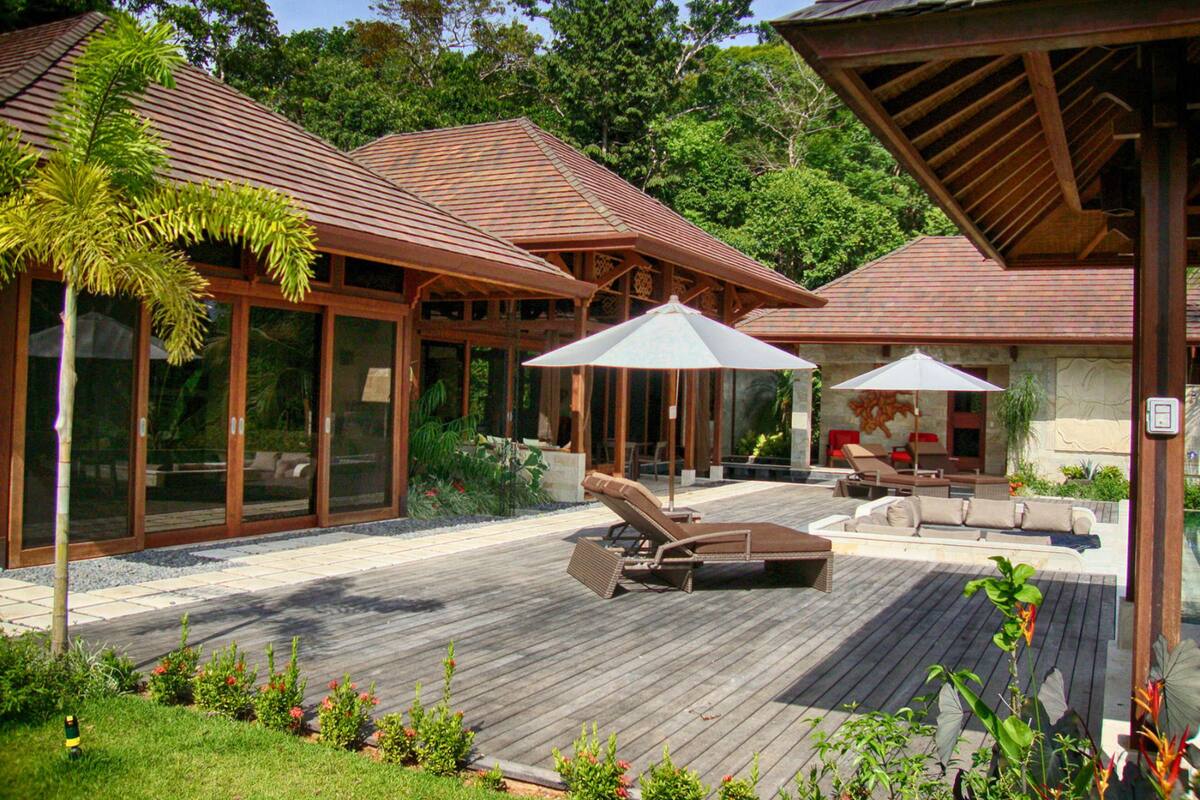 A resort with a wooden deck, outdoor seating, and a covered area with umbrellas.