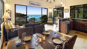 Un comedor con vistas al océano, una cocina con armarios de madera oscura y un ventilador de techo.