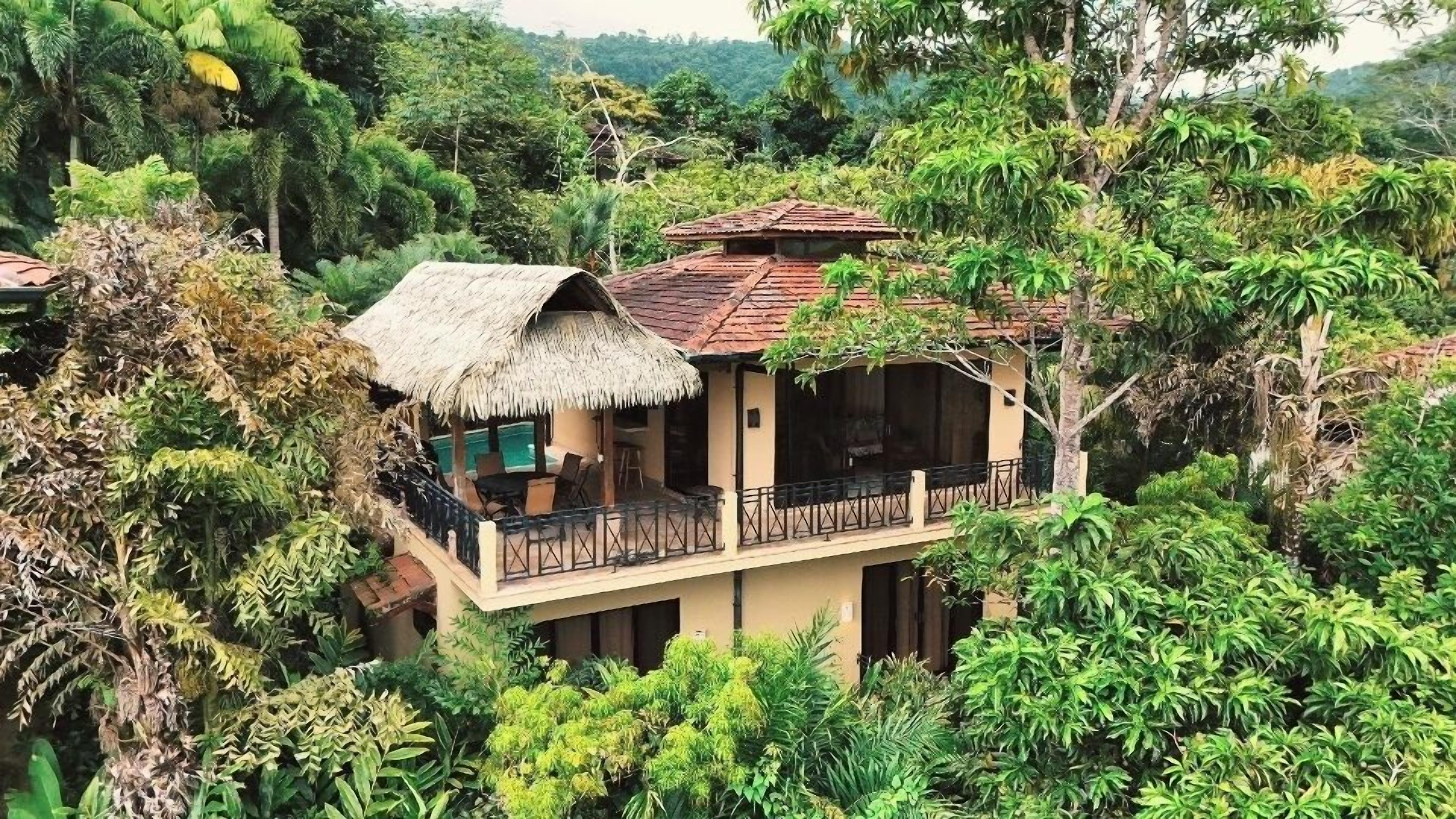 A two-story building with a thatched-roof structure and a balcony.