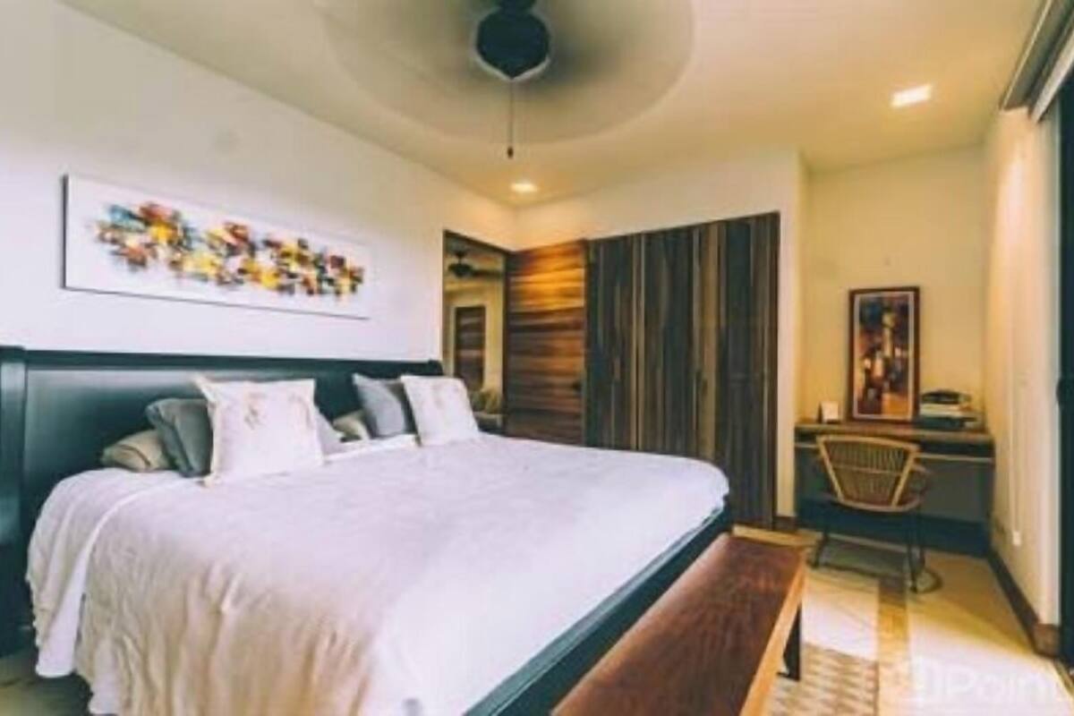 A bedroom with a large bed, a desk, and a chair.