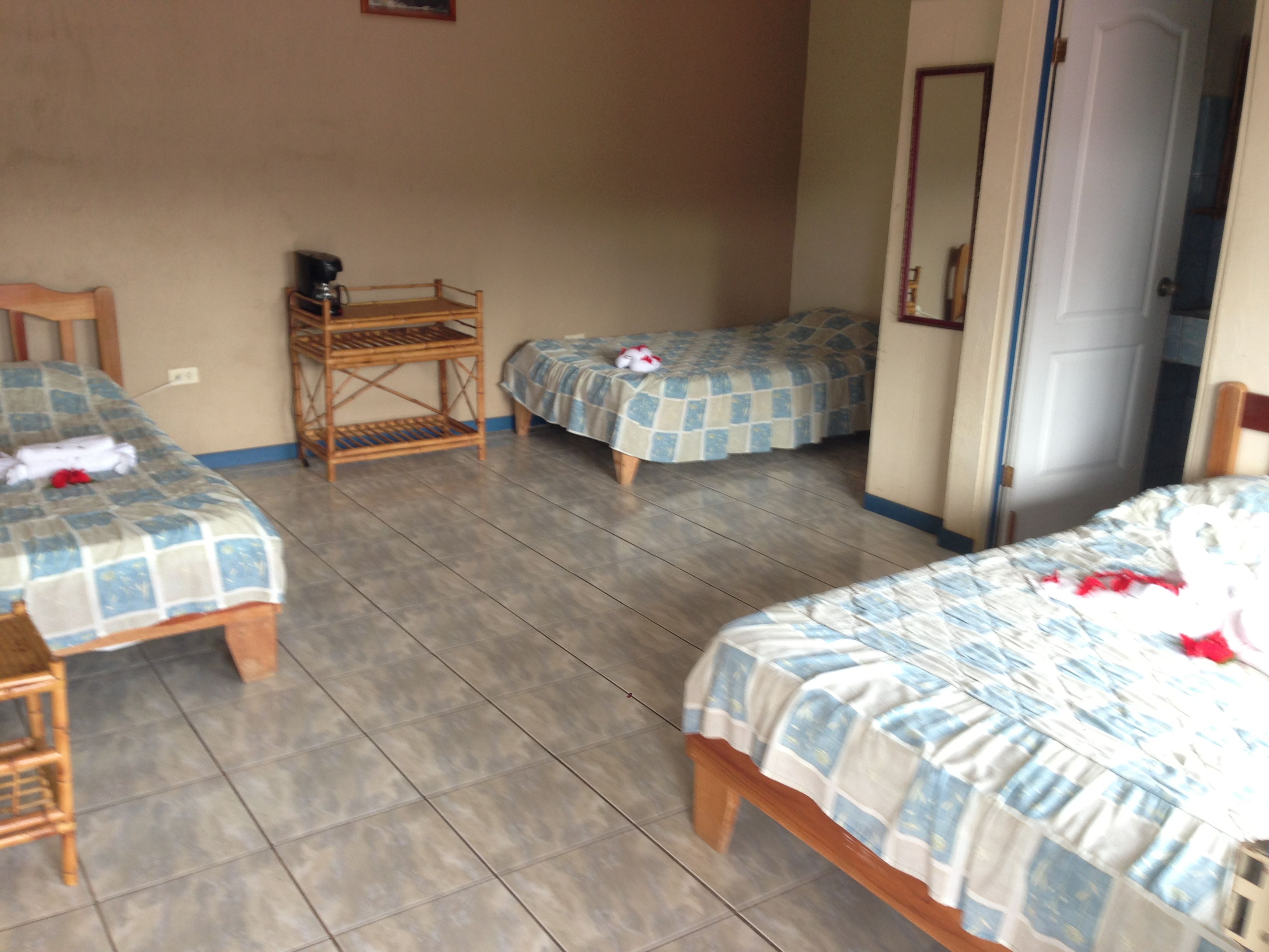 A room with two beds, a small table with a chair, and a door.