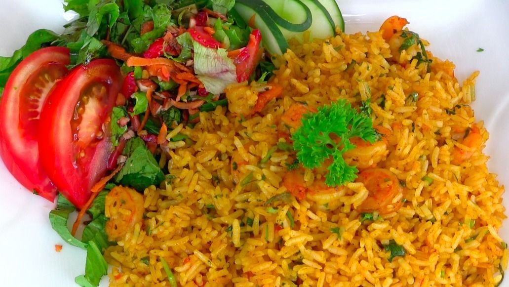 Ein Teller mit gelbem Reis, Gemüse und einem kleinen Salat.