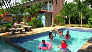 A swimming pool area with a pool, lounge chairs, and palm trees.
