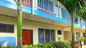 A two-story building with a balcony, a wooden door, and a window.
