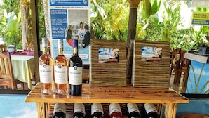 A wooden wine rack with various bottles of Viu Manent wine, a sign with preventive health advice, and a large vase.