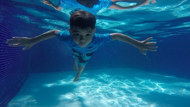 A child swimming underwater in a pool.