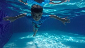 Un niño nadando bajo el agua en una piscina.