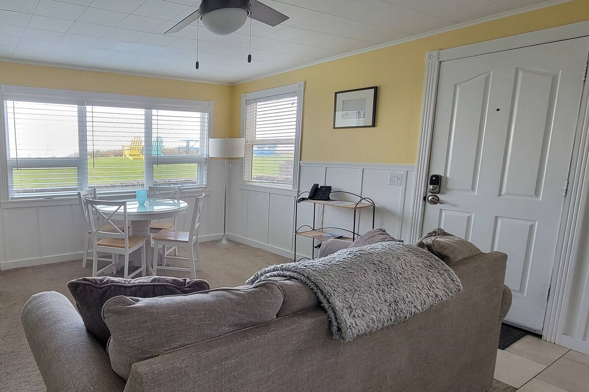Un salon avec une cheminée, un canapé, un fauteuil à motifs et une table à manger avec des chaises.